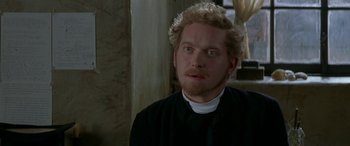 Movie still from “Oscar and Lucinda” (1997), directed by Gillian Armstrong – A man in a priest's outfit looking at the camera; Close Up shot, Over the shoulder angle