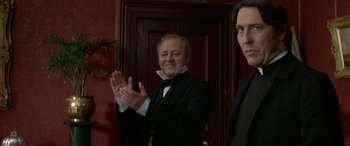 Movie still from “Oscar and Lucinda” (1997), directed by Gillian Armstrong – A man standing next to another man wearing a suit; Medium shot, Low angle
