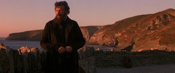Movie still from “Oscar and Lucinda” (1997), directed by Gillian Armstrong – A man standing in front of a cliff with a mountain in the background; Medium shot, Low angle