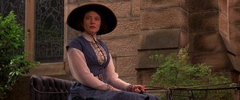 Movie still from “Oscar and Lucinda” (1997), directed by Gillian Armstrong – A woman sitting on top of a bench wearing a hat; Close Up shot, High angle