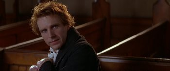 Movie still from “Oscar and Lucinda” (1997), directed by Gillian Armstrong – A man sitting in front of a wooden pews; Close Up shot, Over the shoulder angle