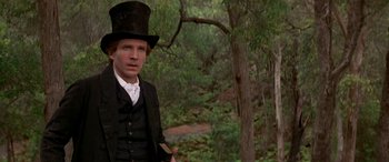 Movie still from “Oscar and Lucinda” (1997), directed by Gillian Armstrong – A man wearing a top hat and a suit in a forest; Close Up shot, Over the shoulder angle