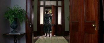 Movie still from “Oscar and Lucinda” (1997), directed by Gillian Armstrong – A woman opens the door of a house to enter; Wide shot, High angle