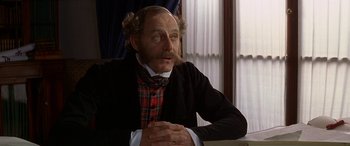 Movie still from “Oscar and Lucinda” (1997), directed by Gillian Armstrong – An older man wearing a plaid shirt and a black jacket; Close Up shot, Over the shoulder angle