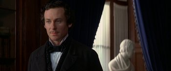 Movie still from “Oscar and Lucinda” (1997), directed by Gillian Armstrong – A person wearing a suit and a bow tie; Close Up shot, Over the shoulder angle