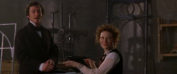 Movie still from “Oscar and Lucinda” (1997), directed by Gillian Armstrong – A woman sitting at a table in a room; Medium shot, Over the shoulder angle