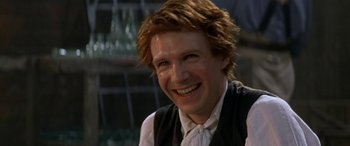 Movie still from “Oscar and Lucinda” (1997), directed by Gillian Armstrong – A person wearing a vest and smiling; Close Up shot, Over the shoulder angle