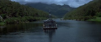 Movie still from “Oscar and Lucinda” (1997), directed by Gillian Armstrong – A boat floating on a body of water near mountains; Extreme Wide shot, High angle
