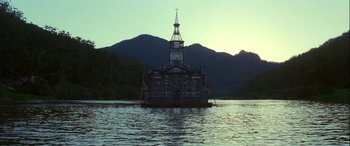 Movie still from “Oscar and Lucinda” (1997), directed by Gillian Armstrong – A boat floating on a body of water near a mountain range; Extreme Wide shot, Low angle