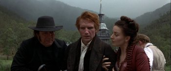 Movie still from “Oscar and Lucinda” (1997), directed by Gillian Armstrong – Two men and a woman standing next to each other in front of a building; Medium shot, Over the shoulder angle