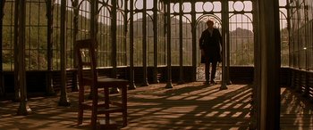 Movie still from “Oscar and Lucinda” (1997), directed by Gillian Armstrong – A person standing in a room with a chair; Wide shot, Low angle