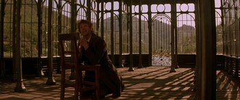 Movie still from “Oscar and Lucinda” (1997), directed by Gillian Armstrong – A man sitting on a chair in front of a window; Wide shot, Low angle