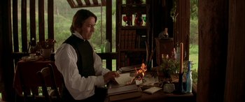 Movie still from “Oscar and Lucinda” (1997), directed by Gillian Armstrong – A man sitting at a desk with a fire in front of him; Medium shot, High angle