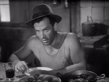 Movie still from “Obsession” (1943), directed by Luchino Visconti – A black and white photo of a man eating food; Close Up shot, Low angle