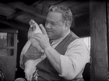 Movie still from “Obsession” (1943), directed by Luchino Visconti – A man holding a chicken in his hands; Medium shot, Low angle