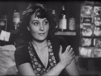 Movie still from “Obsession” (1943), directed by Luchino Visconti – A black - and - white photo of a woman with her arms crossed; Close Up shot, Over the shoulder angle