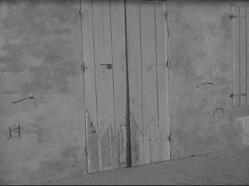 Movie still from “Obsession” (1943), directed by Luchino Visconti – A black and white photo of a door; Wide shot, High angle