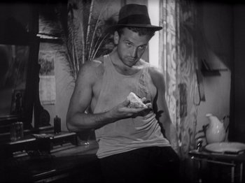 Movie still from “Obsession” (1943), directed by Luchino Visconti – A black and white photo of a man holding a piece of food; Medium shot, Low angle