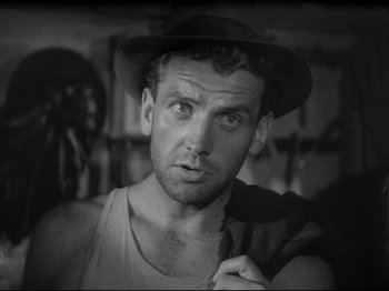 Movie still from “Obsession” (1943), directed by Luchino Visconti – A black and white photo of a man wearing a hat; Close Up shot, Low angle