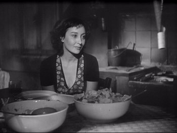 Movie still from “Obsession” (1943), directed by Luchino Visconti – A black and white photo of a woman sitting at a table with bowls of food; Medium shot, High angle