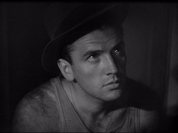 Movie still from “Obsession” (1943), directed by Luchino Visconti – Black and white photograph of a man wearing a hat; Close Up shot, Low angle