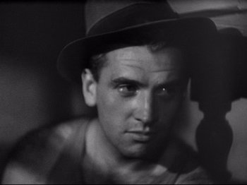Movie still from “Obsession” (1943), directed by Luchino Visconti – A black and white photo of a man wearing a hat; Close Up shot, Low angle
