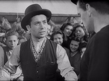 Movie still from “Obsession” (1943), directed by Luchino Visconti – An old photo of a man wearing a hat and a vest; Medium shot, Low angle