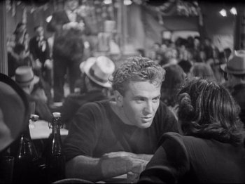 Movie still from “Obsession” (1943), directed by Luchino Visconti – A black and white photo of a man sitting at a table; Medium shot, Over the shoulder angle