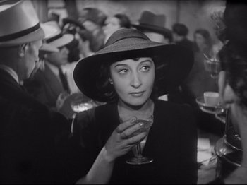 Movie still from “Obsession” (1943), directed by Luchino Visconti – A woman wearing a hat and holding a glass of wine; Close Up shot, High angle
