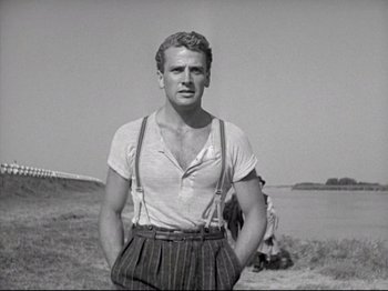 Movie still from “Obsession” (1943), directed by Luchino Visconti – A black and white photo of a man in a white shirt and suspenders; Medium shot, Low angle
