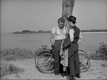 Movie still from “Obsession” (1943), directed by Luchino Visconti – A man and a woman standing next to a bicycle; Medium shot, Over the shoulder angle