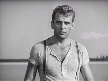 Movie still from “Obsession” (1943), directed by Luchino Visconti – Black and white photograph of a man wearing suspenders; Medium shot, Low angle