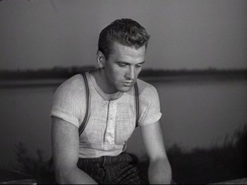 Movie still from “Obsession” (1943), directed by Luchino Visconti – A man sitting on the ground wearing suspenders; Medium shot, Low angle