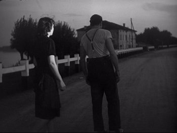 Movie still from “Obsession” (1943), directed by Luchino Visconti – A man and a woman walking down a road; Wide shot, Low angle