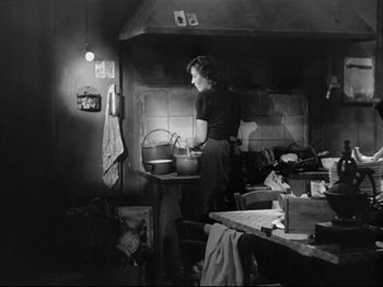 Movie still from “Obsession” (1943), directed by Luchino Visconti – An old photo of a woman cooking in a kitchen; Medium shot, Low angle
