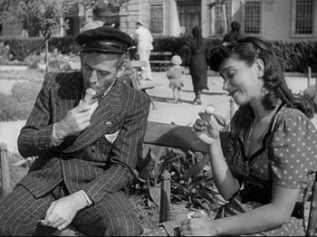 Movie still from “Obsession” (1943), directed by Luchino Visconti – A man and a woman sitting next to each other on a bench; Medium shot, High angle