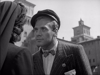 Movie still from “Obsession” (1943), directed by Luchino Visconti – A black and white photo of a man in a suit and hat; Close Up shot, Low angle