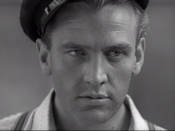 Movie still from “Obsession” (1943), directed by Luchino Visconti – A black and white photo of a man wearing a hat; Close Up shot, Low angle