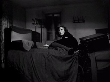 Movie still from “Obsession” (1943), directed by Luchino Visconti – A woman sitting on a bed in a dark room; Wide shot, High angle