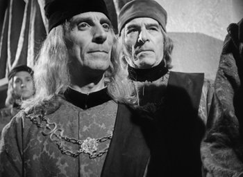 Movie still from “Othello” (1951), directed by Orson Welles – A couple of men standing next to each other; Medium shot, Over the shoulder angle