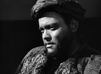 Movie still from “Othello” (1951), directed by Orson Welles – A black and white photo of a man wearing a hat; Close Up shot, Low angle