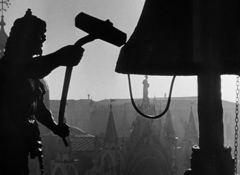 Movie still from “Othello” (1951), directed by Orson Welles – A man is holding a hammer in a black and white photo; Medium shot, Low angle