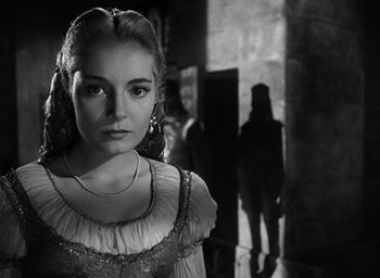 Movie still from “Othello” (1951), directed by Orson Welles – A young woman in a medieval dress looking at the camera; Close Up shot, Over the shoulder angle