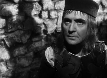 Movie still from “Othello” (1951), directed by Orson Welles – A man in a medieval outfit looking into the distance; Close Up shot, Over the shoulder angle