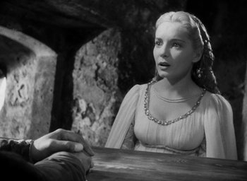 Movie still from “Othello” (1951), directed by Orson Welles – A woman in a white dress sitting in front of a table; Close Up shot, Over the shoulder angle
