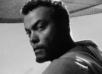 Movie still from “Othello” (1951), directed by Orson Welles – Black and white photograph of a man looking at the camera; Close Up shot, Low angle