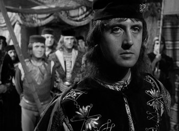 Movie still from “Othello” (1951), directed by Orson Welles – A group of men standing next to each other in a room; Close Up shot, Over the shoulder angle