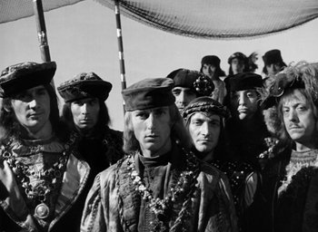 Movie still from “Othello” (1951), directed by Orson Welles – A black and white photo of a group of men in medieval garb; Medium shot, High angle