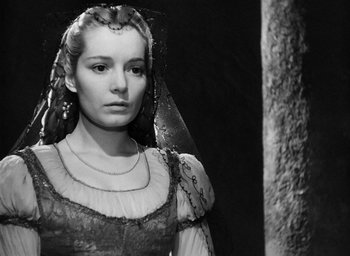 Movie still from “Othello” (1951), directed by Orson Welles – A black and white photo of a woman in a medieval dress; Close Up shot, Over the shoulder angle