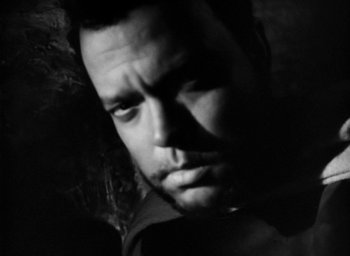 Movie still from “Othello” (1951), directed by Orson Welles – Black and white photograph of a man in a dark room; Close Up shot, Low angle
